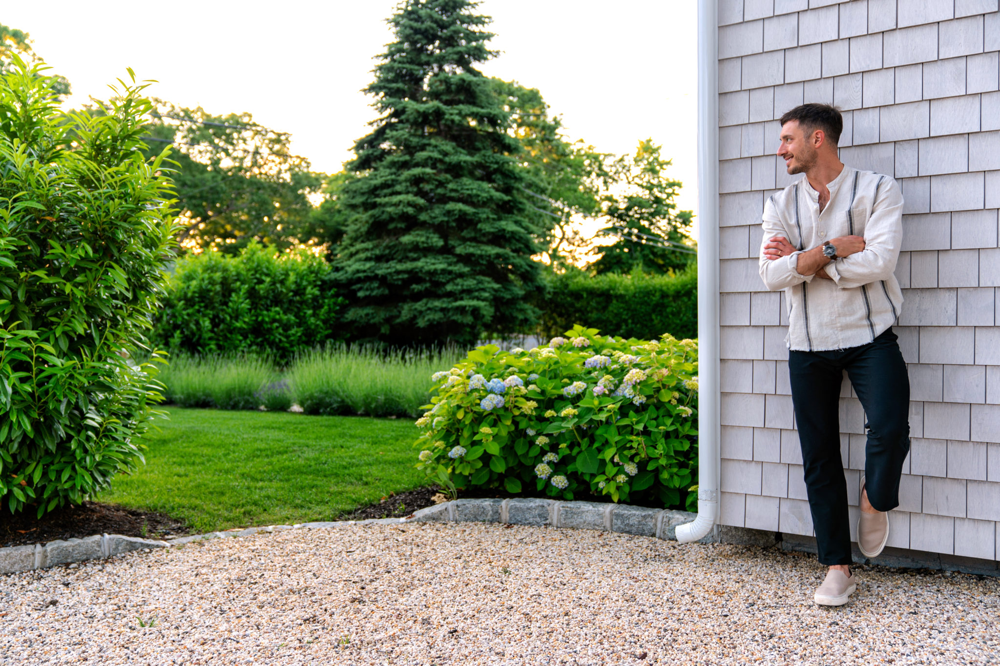 Man wearing linen shirt in front of shingle house